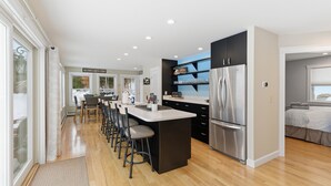 A modern kitchen with a central island, stainless steel appliances, and a bar seating area. - Enjoy private and pristine access to the Pemigewasset River from THE RIVER VIEW… (Campton)