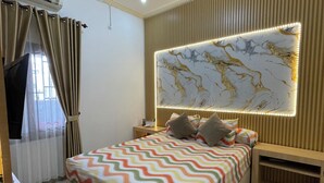 Ein modernes Schlafzimmer mit einem großen Bett, einem an der Wand montierten Fernseher und einer Deckenleuchte.