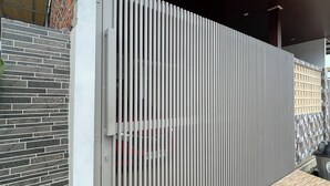 Ein modernes Gebäude mit weißem Zaun, einer Ziegelwand und einer Holzterrasse.