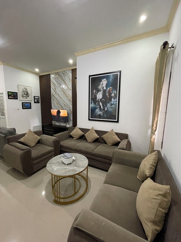 A modern living room with a sectional sofa, a coffee table, and a flat-screen TV.