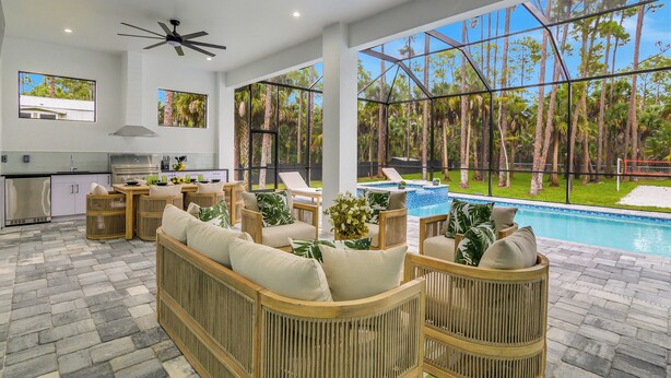 A spacious indoor area with a pool, wicker furniture, and a kitchen area. - The Naples Luxe Retreat . Game Room • Heated Pool (Naples)