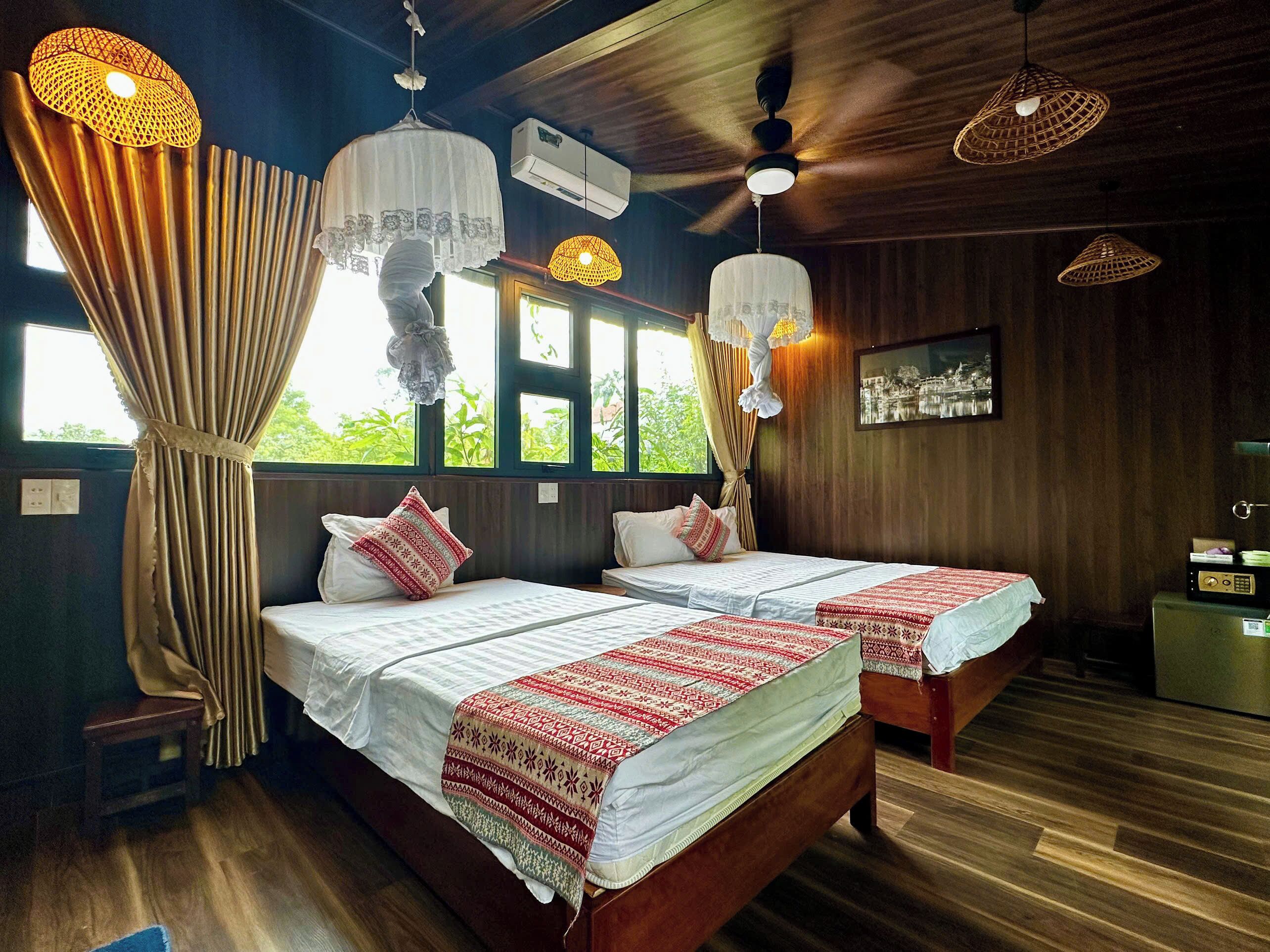 A room with two beds, a ceiling fan, and a window with curtains.