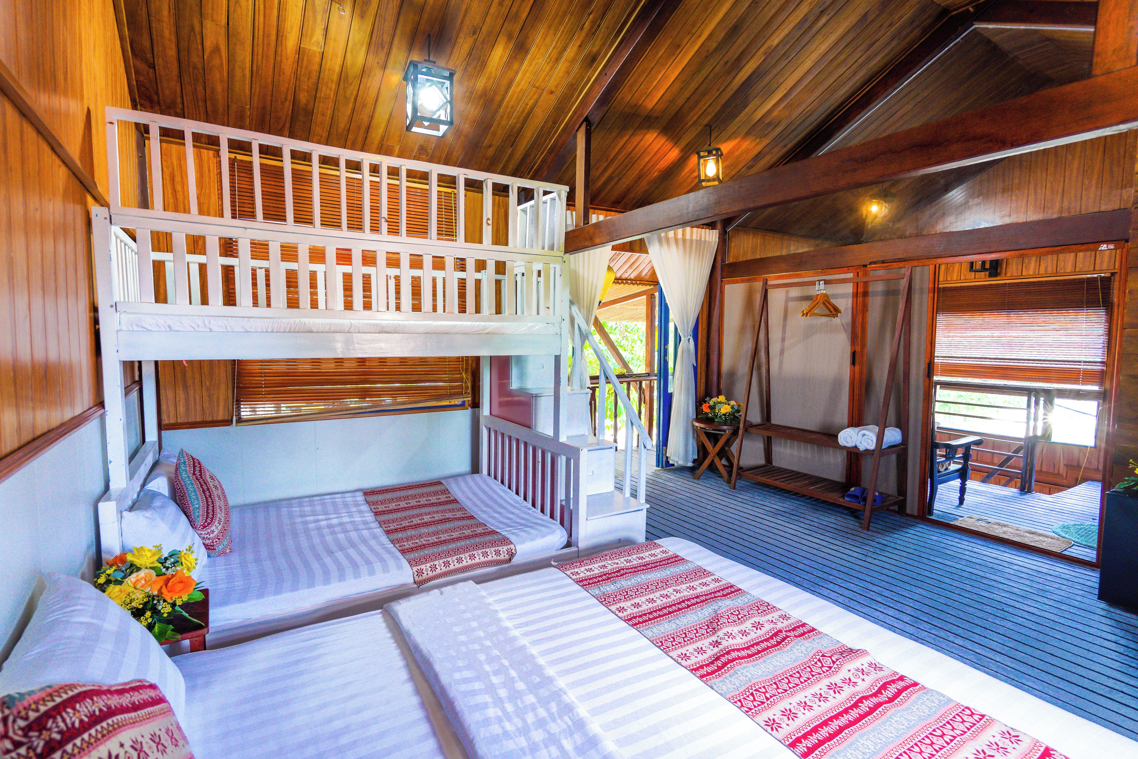 A room with bunk beds, a small table with a chair, and a window with curtains.