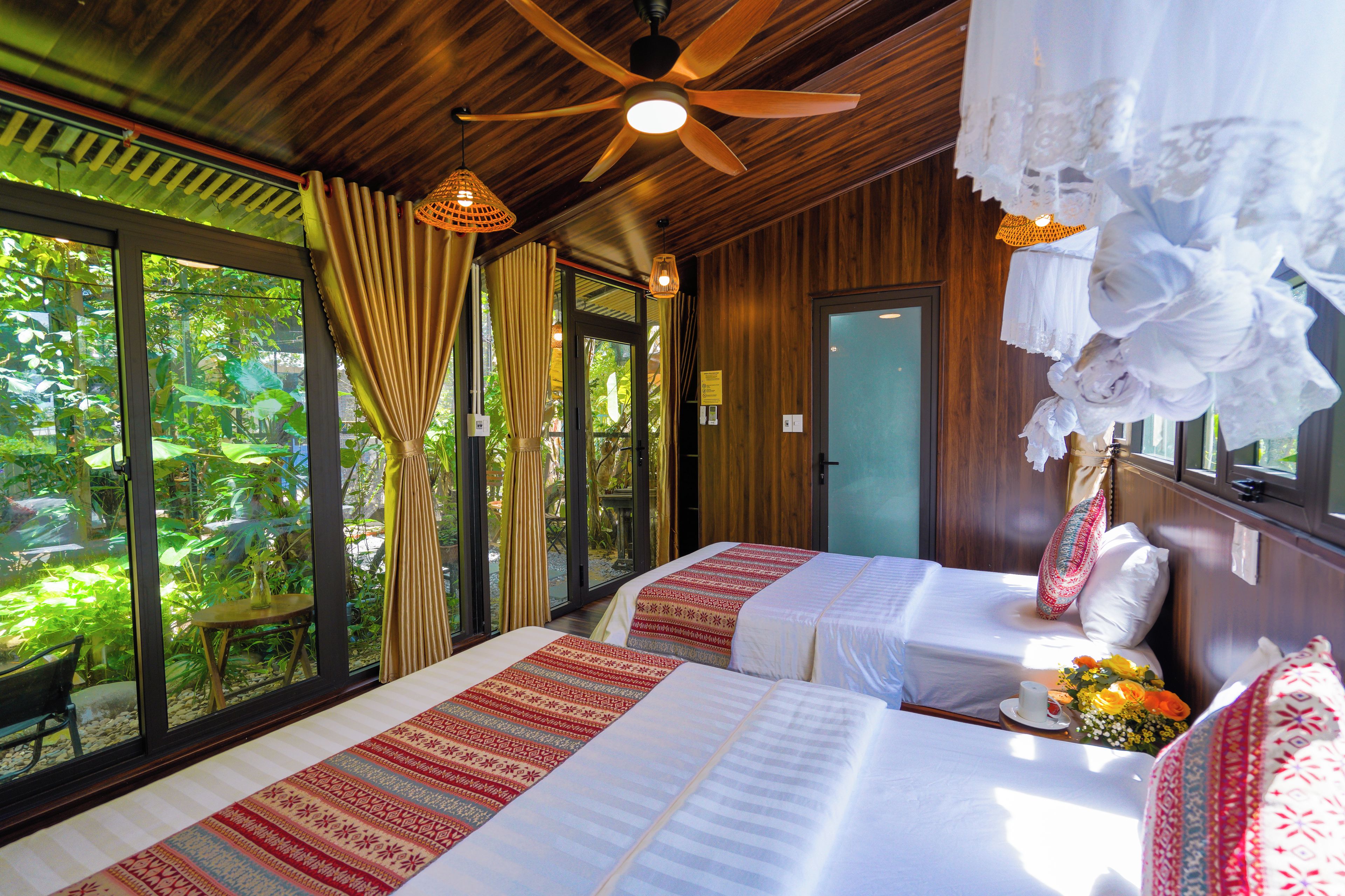 Habitación con dos camas, ventilador de techo y vistas al paisaje exterior.