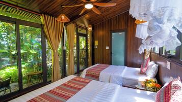 Habitación con dos camas, ventilador de techo y vistas al paisaje exterior.