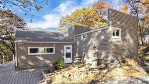 A two-story house with a stone pathway leading to the front door, surrounded by autumn foliage. - 3 Bedroom Dream: Hudson Valley views, Woodbury Commons, West Point & Storm King (Cornwall)