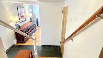 Una scala in legno con corrimano che conduce a una stanza con una panca e un tavolo.