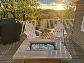 En terrasse med Adirondack-stole, pejse og grill.
