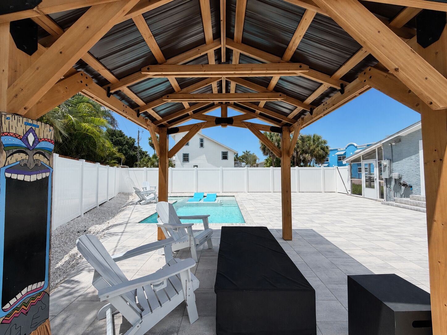 Un espace extérieur abrité comprenant une piscine, des chaises longues et une décoration sur le thème des îles tropicales.