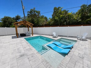 A swimming pool with a wooden pergola and lounge chairs.