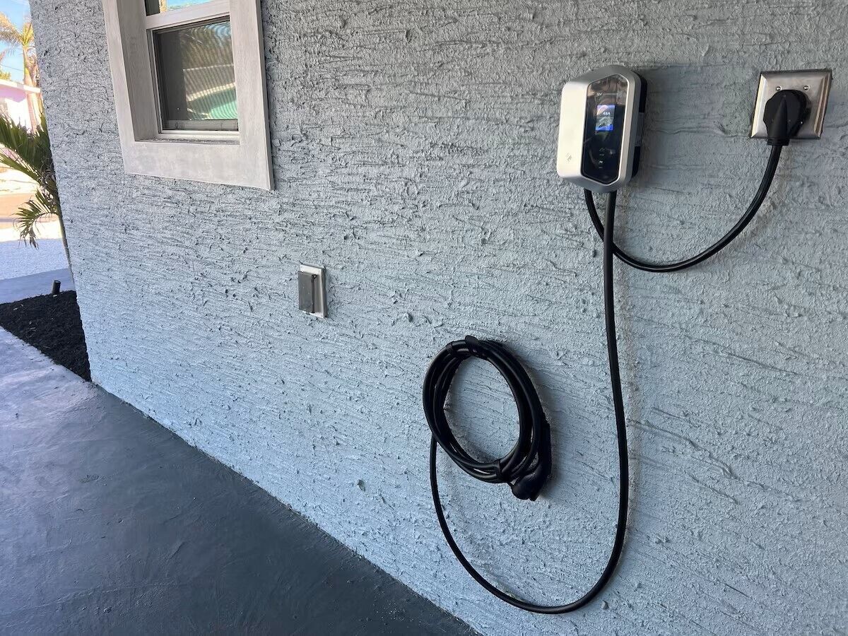 An outdoor electrical outlet with a charging cable connected to a device.