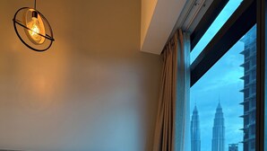 Une chambre d’hôtel avec un lit, une tête de lit, une fenêtre avec des rideaux et une vue sur la ville.