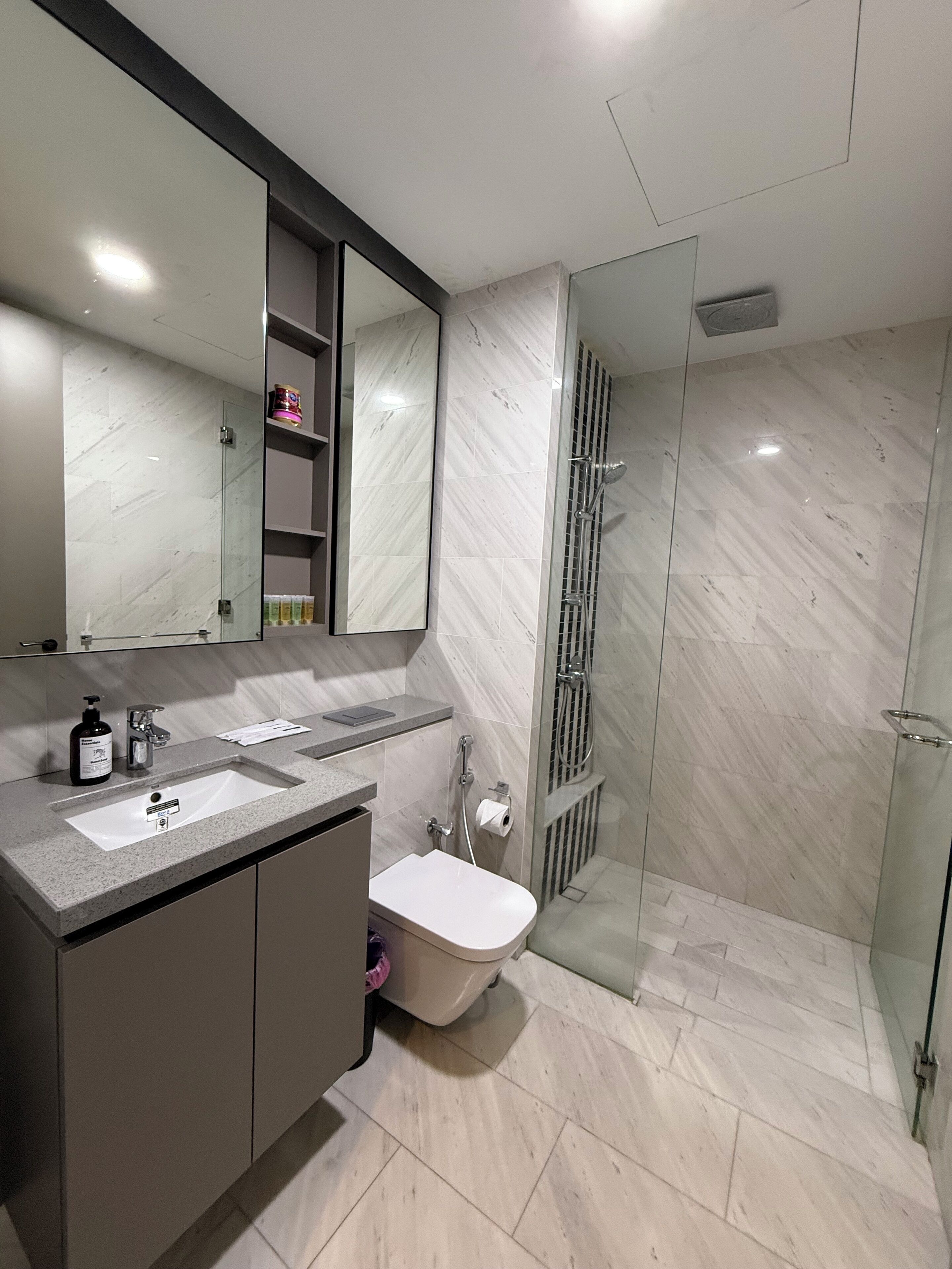 A modern bathroom with two sinks, a toilet, and a glass-enclosed shower.