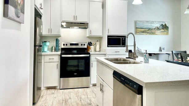 A modern kitchen with white cabinetry, stainless steel appliances, and pendant lighting. - Peaceful 2-bedroom townhome -Sleeps 6 in La Feria (La Feria)