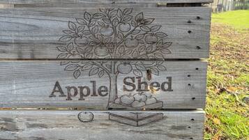 A wooden sign with a tree and apples, labeled 'Apple Shed.'