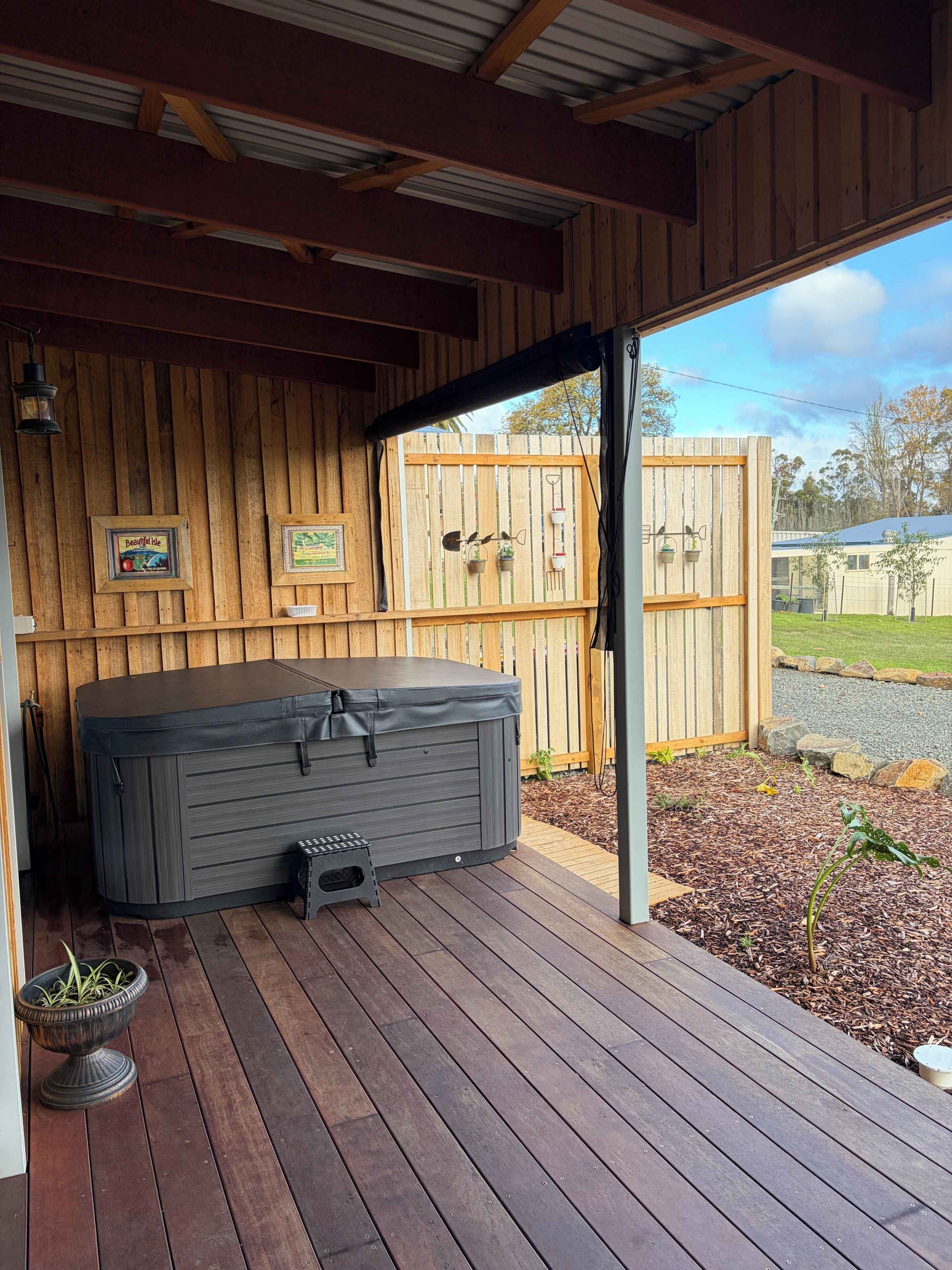 Ein Whirlpool auf einer Holterrasse mit Holzzaun und einem gerahmten Bild im Hintergrund.