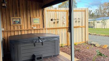 Ein Whirlpool auf einer Holterrasse mit Holzzaun und einem gerahmten Bild im Hintergrund.