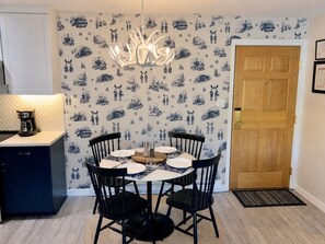 A dining area with a round table, black chairs, and a chandelier.