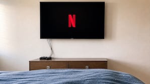 Ein Schlafzimmer mit einem Bett, einem an der Wand montierten Fernseher und einer Holzkommode.