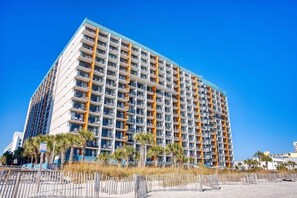 A multi-story hotel with balconies, a beach view, and palm trees in the foreground. - Landmark 1036 (Myrtle Beach)