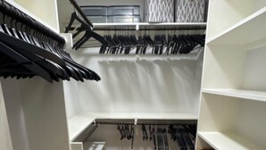 Un vestidor con estantes abiertos, espacio para colgar ropa y suelo de madera.