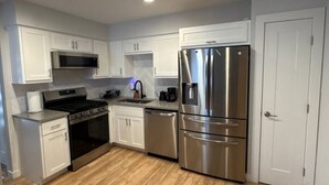 Una cocina moderna con armarios blancos, electrodomésticos de acero inoxidable y piso de madera.