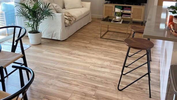 Una sala de estar moderna con sofá, televisor y zona de comedor con sillas y una mesa.