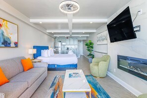 Une chambre d’hôtel moderne équipée d’un lit, d’un canapé, d’une télévision, d’une cheminée et d’un coin cuisine.