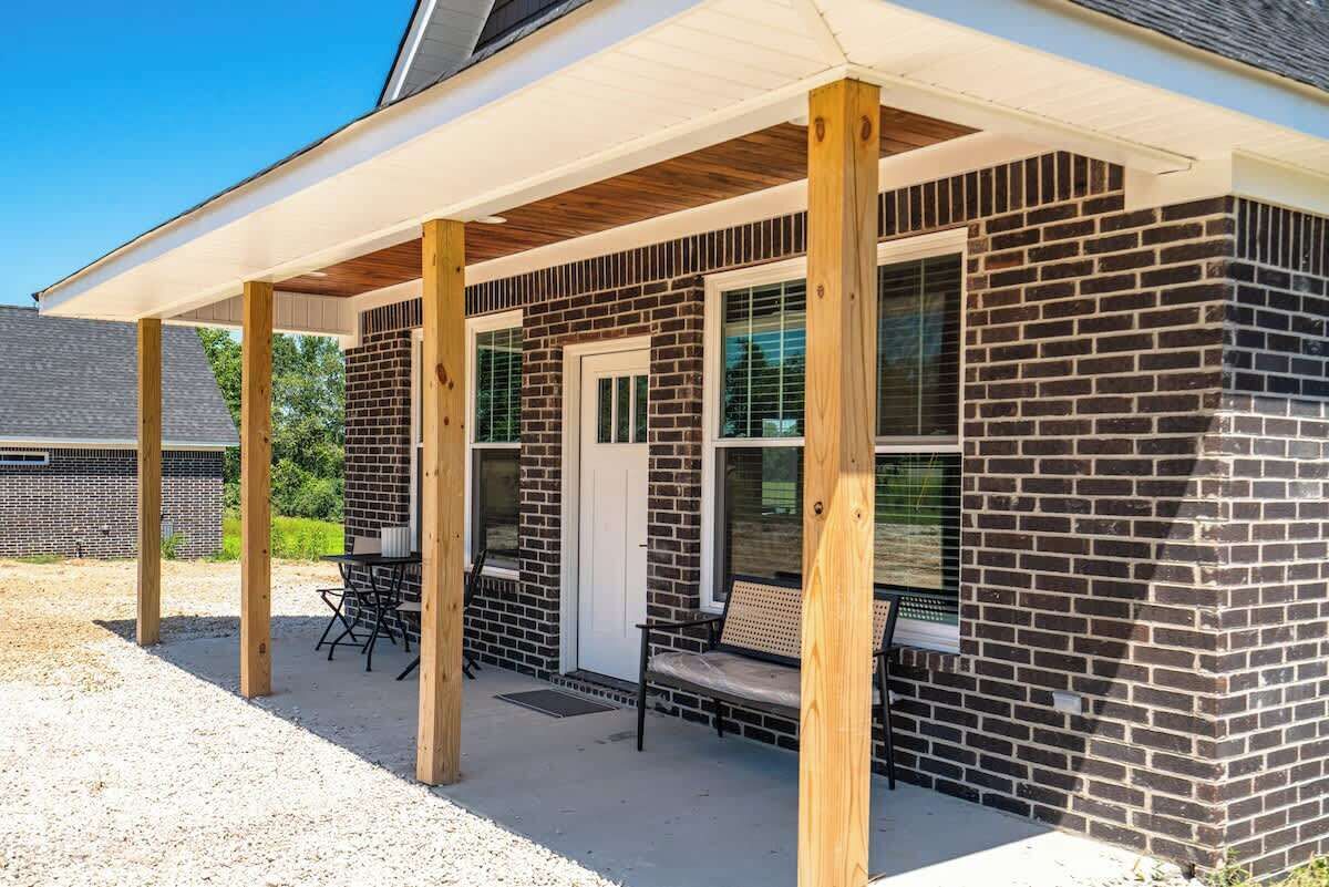 A brick building with a covered patio, a door, and two windows.
