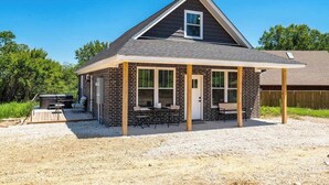 Ein Bungalow mit überdachter Terrasse, Grill und kleiner Holzterrasse.