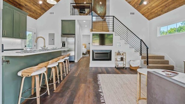 Eine moderne Küche mit Barhocker, Kamin und einer Treppe zu einer oberen Ebene.