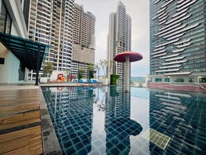 Piscina en la azotea con vistas a rascacielos, sillas de descanso y zona de juegos para niños.