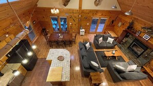 A log cabin interior with a dining area, sofas, a fireplace, and deer antlers mounted on the walls. - 4-bedroom 3 full bath, house in amazing Lake Geneva with AC. (Lake Geneva)