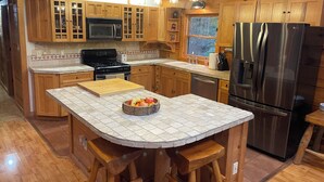 A modern kitchen with wooden cabinets, a stainless steel refrigerator, a stove, and a large island with stools. - 4-bedroom 3 full bath, house in amazing Lake Geneva with AC. (Lake Geneva)