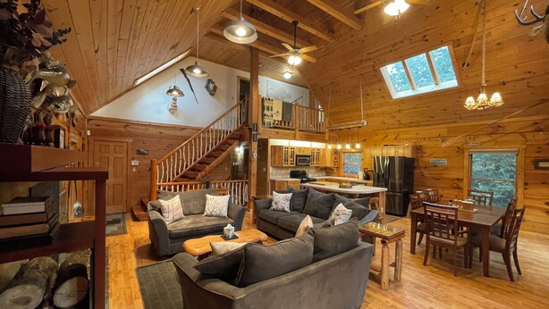 A spacious cabin interior with a wooden interior, a dining area, a kitchen, and a staircase leading to an upper level. - 4-bedroom 3 full bath, house in amazing Lake Geneva with AC. (Lake Geneva)