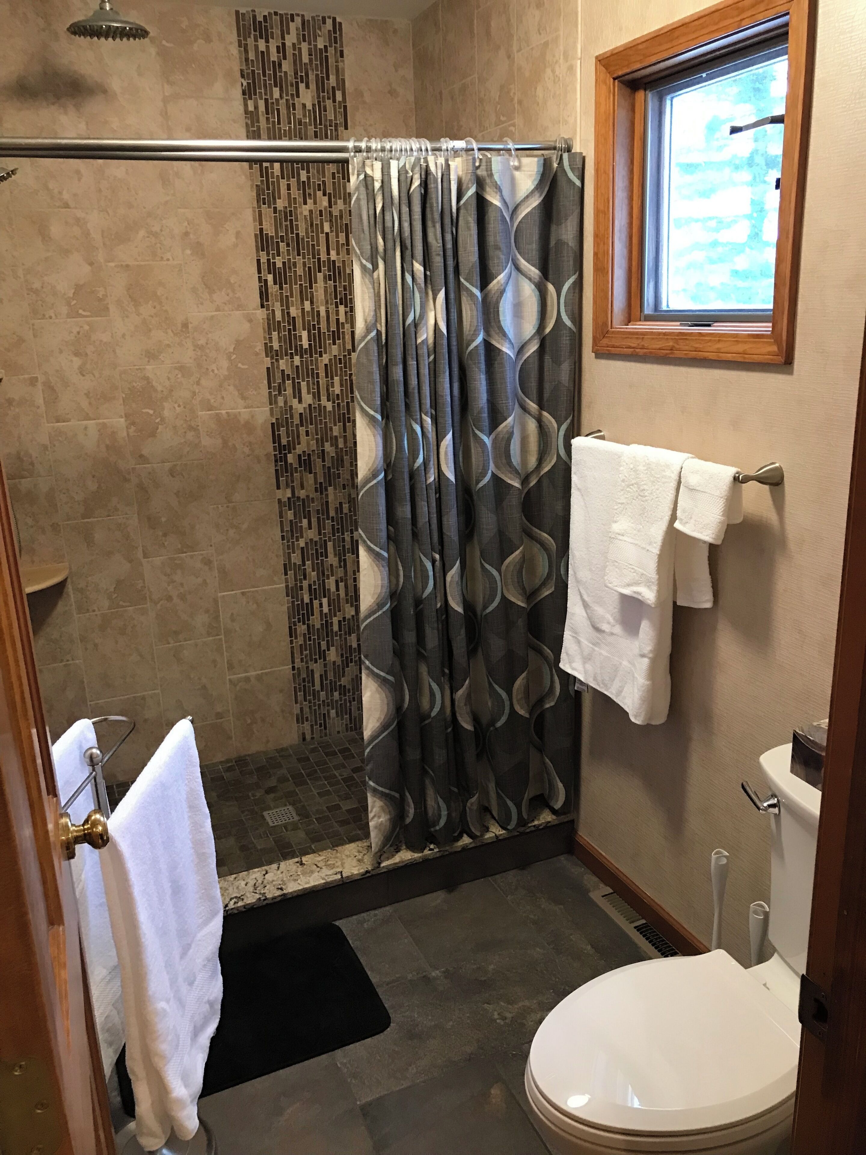 Baño con ducha, inodoro y ventana.