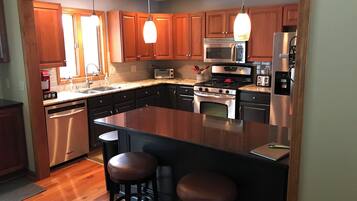 Une cuisine moderne avec des meubles en bois, des appareils en acier inoxydable et un îlot central doté de tabourets.