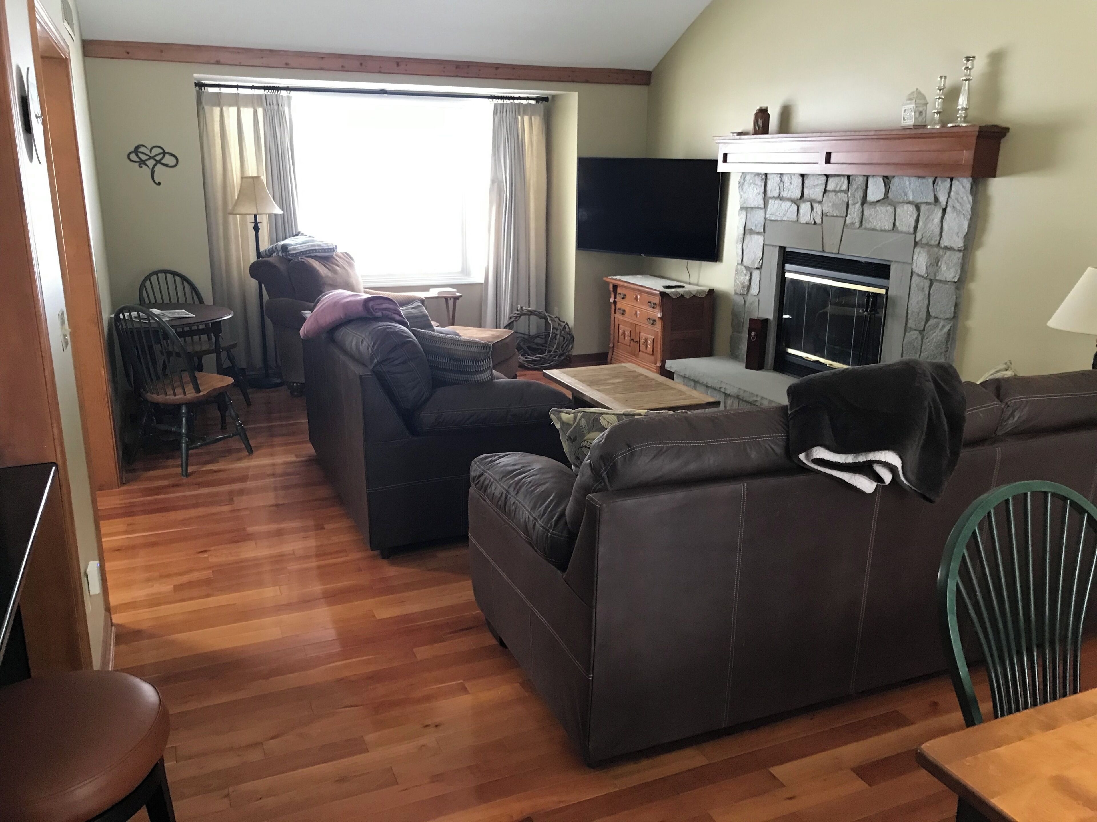 Un salon avec une cheminée, un téléviseur et un coin repas comprenant des chaises et une table.