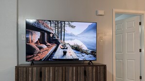 Televisio on sijoitettu puiseen telineeseen, ja sen edessä avautuu upea näkymä vuoristomaisemaan.