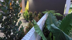 Ein modernes Gebäude mit flachem Dach, umgeben von Pflanzen und einem weißen Zaun.