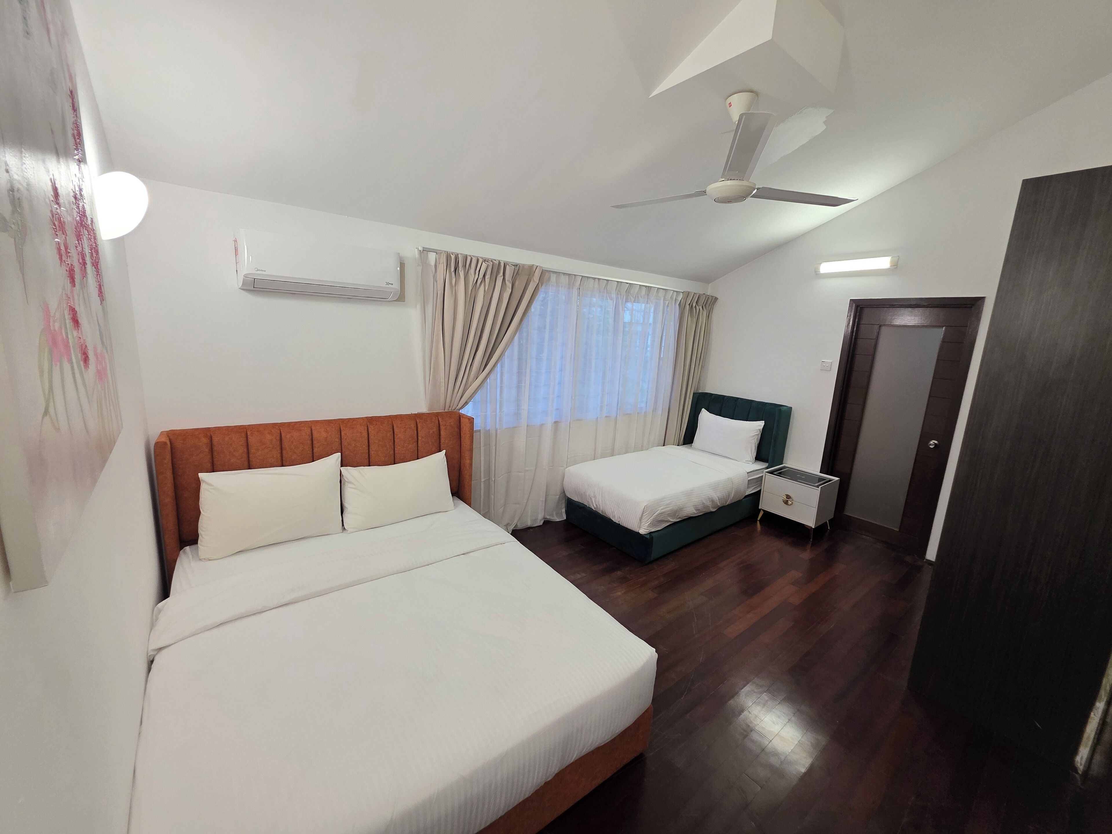 A hotel room with a large bed, a smaller bed, a nightstand, a ceiling fan, and a door.
