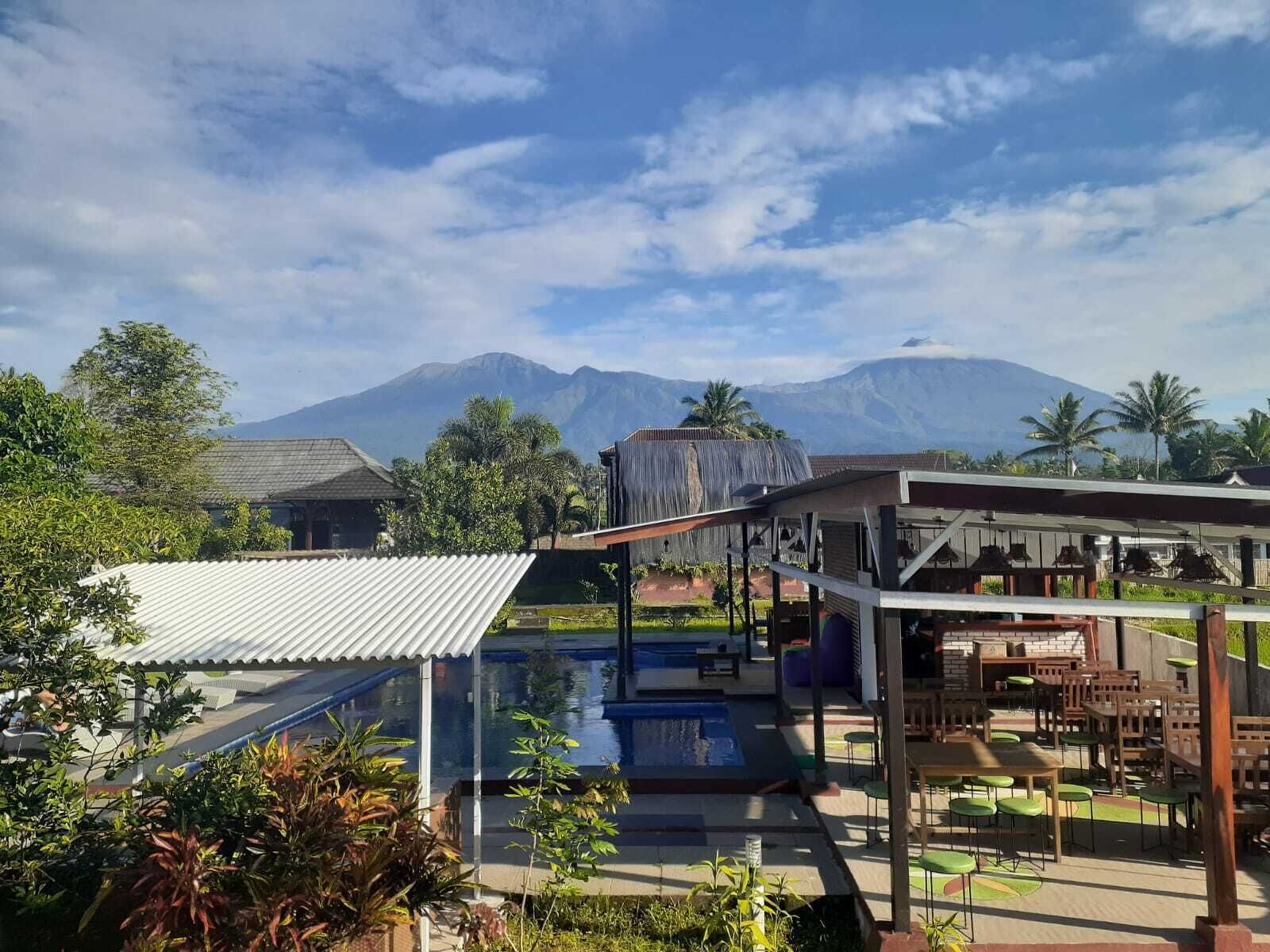 A resort with a pool, outdoor seating, and a mountain view.