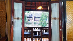 A room with a wooden ceiling, a large open door leading outside, and a view of a traditional building. - Green Orry Inn Villas & Resort (Tetebatu)