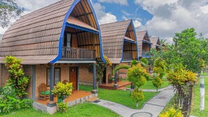 A row of wooden cabins with pitched roofs, each featuring a balcony and a small porch area. - Green Orry Inn Villas & Resort (Tetebatu)
