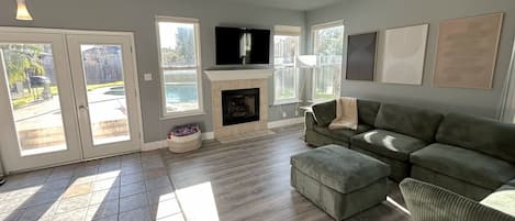 A living room with a fireplace, a television, and a ceiling fan.