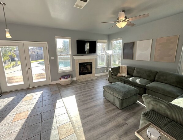 A living room with a fireplace, a television, and a ceiling fan. - Denise Dr (Austin)