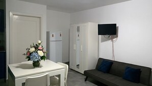 Un espacio habitable compacto con kitchenette, comedor y zona de estar.