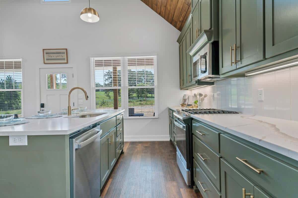 A modern kitchen with a large island, built-in appliances, and a view of the outdoors.