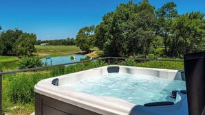 Een hottub met uitzicht op een meer en omliggende begroeiing.