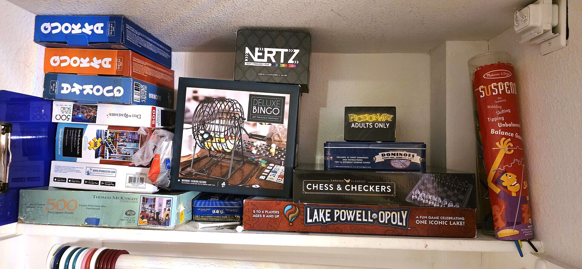 A shelf with various board games and puzzles.
